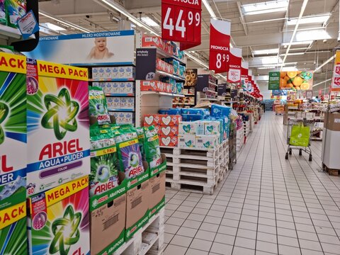 Artykuły papiernicze i kosmetyki na regale sklepu wielkiego marketu z widocznymi cenami. 