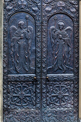 dark gray metal door to the Georgian church with the image of angels close-up front view