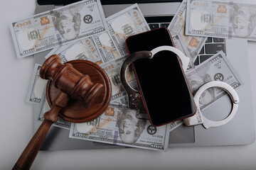 Top view of smartphone with handcuff on a dollar banknotes and laptop. Cyber crime and law concept