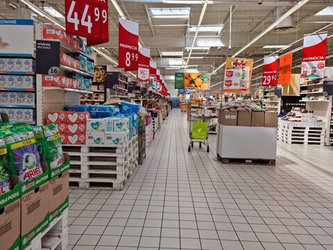 Artykuły papiernicze i kosmetyki na regale sklepu wielkiego marketu z widocznymi cenami. 