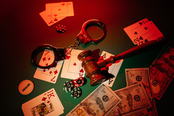 Playing cards, handcuffs, gavel and chips on green table. Prohibited gambling concept
