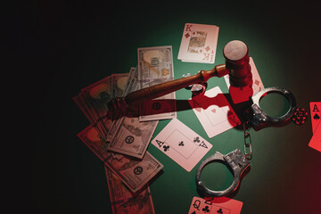 Casino and poker concept with cards, handcuffs, wooden gavel and chips on the green table