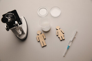 A syringe, wooden couple and microscope at laboratory. Pregnancy, healt care and analysis concept