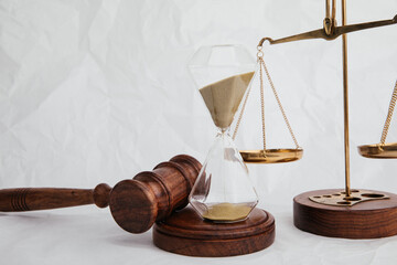 Wooden judge gavel with hourglass and scales on light background