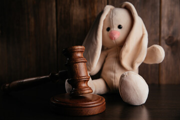 Wooden gavel and plush bunny in a dark court room. Law and children concept