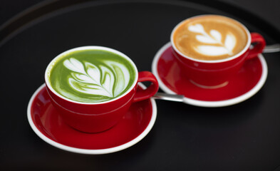 Matcha latte and coffee late red cup stand on the black table. Nutrition. Herbal.