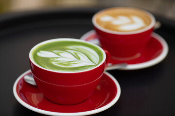 Matcha latte and coffee late red cup stand on the black table. Nutrition. Herbal.