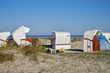 Fototapeta na wymiar muddy boots stand in front of white beach chairs at the North Sea coast in Schillig, Germany