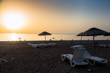 White tourist sunbeds on the beach featuring a mix of sand & small pebbles in the Mediterranean coast