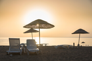 White tourist sunbeds on the beach in the Mediterranean coast during sunset on the Mediterranean sea