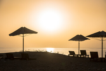 Orrange sunset with sunbeds on a beach, the Mediterranean coast