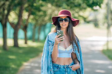 girl with mobile phone in hat and sunglasses on the street outdoors