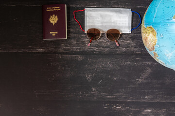 World map and items on wooden background, flat lay. summer travel copy space for text. map, sunglasses, passport, phone, pen,mask, book on wooden background top view. planning vacation concept.