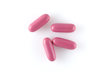 Pink capsules with medical drugs or supplements isolated on white background, top view.