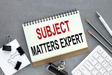 subject matters expert. text on open notepad near white keyboard