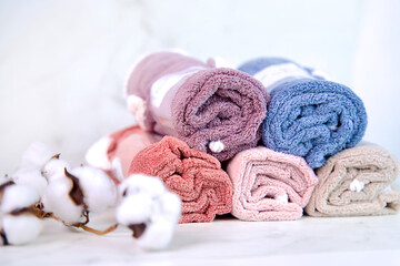 Fototapeta na wymiar Close-up of folded small colored terry towels and a branch of cotton on a light background, personal hygiene products, space for text