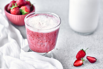 Strawberry coconut milkshake, frappé or smoothie in drinking glass on gray background top view. Healthy vegan diet refreshing drink. Healthy food and drink concept.