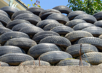Wall of old tires. Unusual decoration of the land. Wheel fence.  Penetration protection