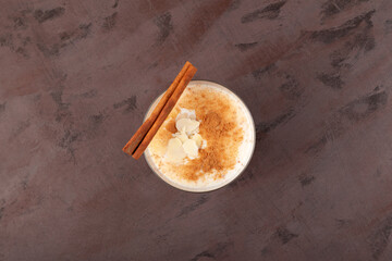 Salep or Sahlep in cup on textured brown surface, top view. Turkish hot drink with cinnamon and spicy. Selective focus, copy space