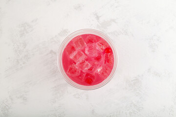 Red refreshing iced cocktail in disposable plastic cup, top view. Summer fruit and berry drink....