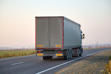 Obraz na płótnie Canvas Semi-truck with cargo trailer driving on highway hauling goods in evening. Delivery transportation and logistics concept