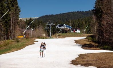 Couple woman and man in stylish casual clothes standing in the snow in the mountains on the background of beautiful scenery of the ski resort.