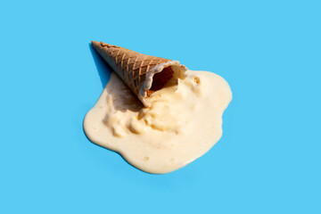 Melting ice cream balls with waffle cone on blue background.