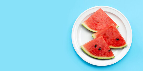 Watermelon slices in white plate on blue background.