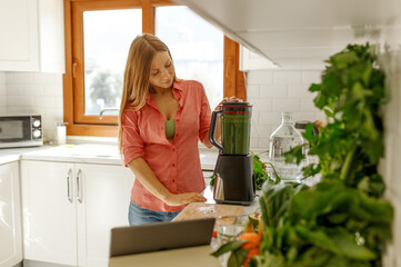 Woman preparing tasty green smoothie in kitchen