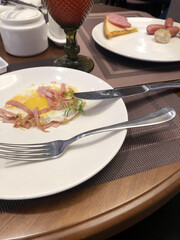 Delicious breakfast white plate with scrambled eggs and ham on a wooden table. Food and drinks