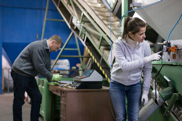 Skilled woman controlling process of olive oil pressing on small factory, looking at gages of equipments