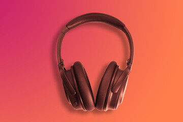 Computer headphones. Black headphones on a orange red background. The concept of listening to music, creating audio, music. Computer work, abstraction and minimalist style.