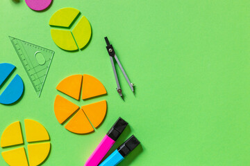Multicolored fractions, rulers, pencils on green background. Interesting, fun math for kids....