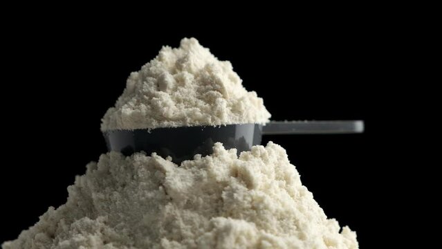 Circular motion of scoop with protein powder on black background.