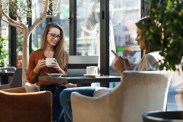 Two young business women in a cafe having one on one meeting. Friends after work talking gossiping...