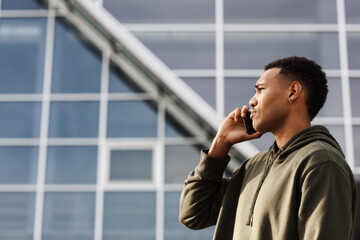 young african american man in casual outfit standing and talking on phone