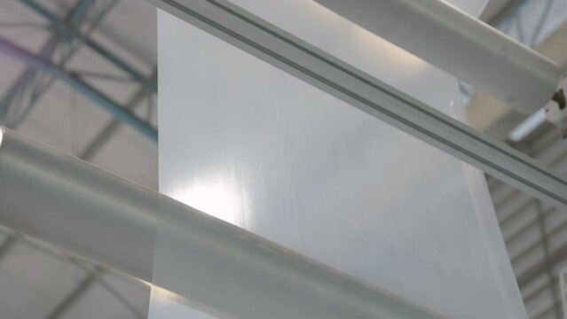 Large plastic film rolling on the machine roller. Plastic film manufacturing process. Multilayer blown film. Static shot, for background and inserts. Plastics, packaging, industrial themes.