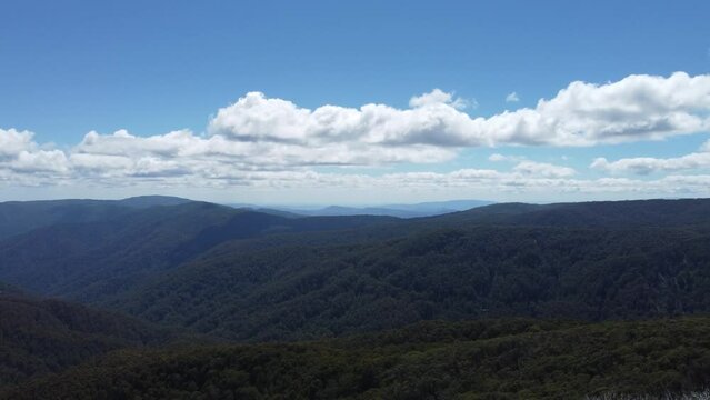 Slow drone boom up to reveal rolling mountains in the Victorian high country in Mt Buller