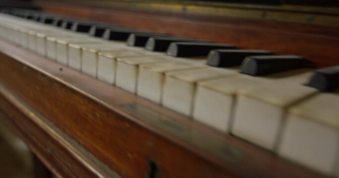 Medium close up of an old vintage piano. Camera moves forward and turn to the right to show the hole keyboard