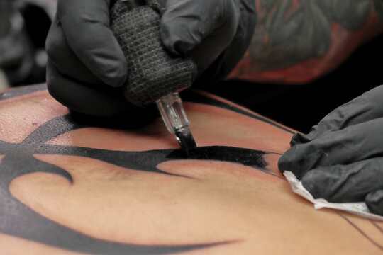 Tatuador en sesión de tatuaje tatuando un tatuaje a una persona