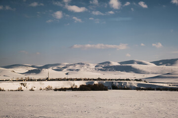 Landscape view of a mountain with snow and a village, blue sky and some clouds