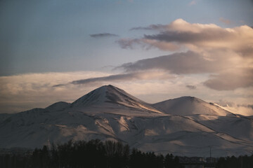 Landscape view of a mountain with snow, blue sky and some clouds