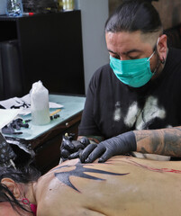 Tatuador en sesión de tatuaje tatuando un tatuaje a una persona