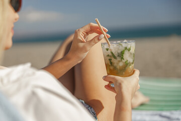 Mojito cocktail with lime and mint in highball glass in female hands
