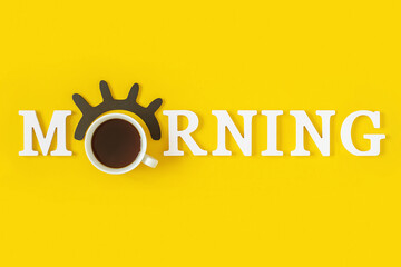 Creative good morning concept. White letters, black eyelashes, alarm clock and cup of coffee on...