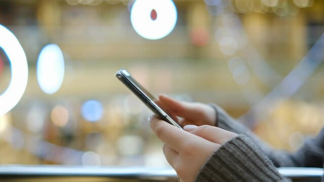 Shopping center. Moll. Finger of woman touching scroll page app on mobile phone. Browsing movie video in the internet library to watch film online.
