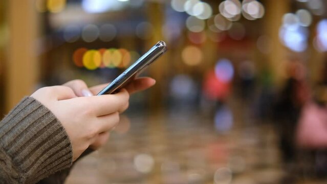 Shopping center. Moll. Finger of woman touching scroll page app on mobile phone. Browsing movie video in the internet library to watch film online.