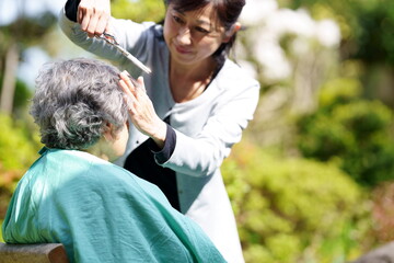 庭でヘアカットしてもらう高齢女性