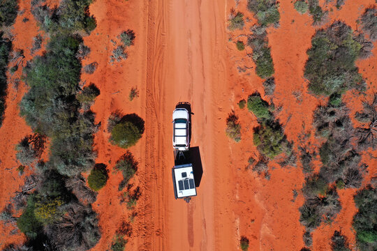Aerial landscape drone view of 4WD vehicle towing an off road caravan driving on a sand dirt road