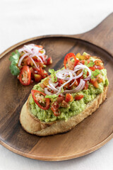 Fototapeta na wymiar spicy chilli avocado guacamole on toast tapas on wood tray